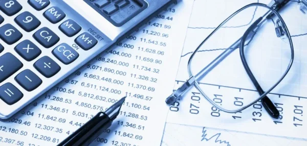 Kalkulator, naočale i olovka na financijskim izvještajima s brojkama