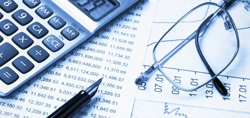 Kalkulator, naočale i olovka na financijskim izvještajima s brojkama