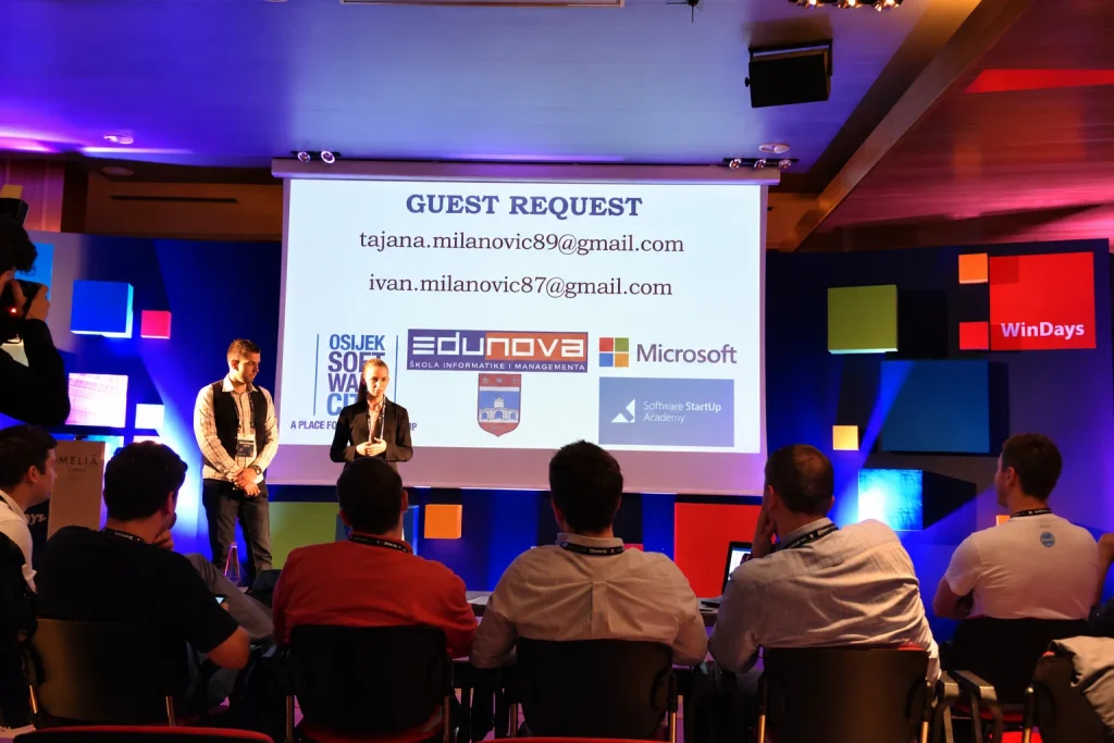Predstavljanje projekta Guest Request na pozornici WinDays konferencije, s publikom u prvom planu i projekcijom loga Edunove, Microsofta i WinDaysa u pozadini.